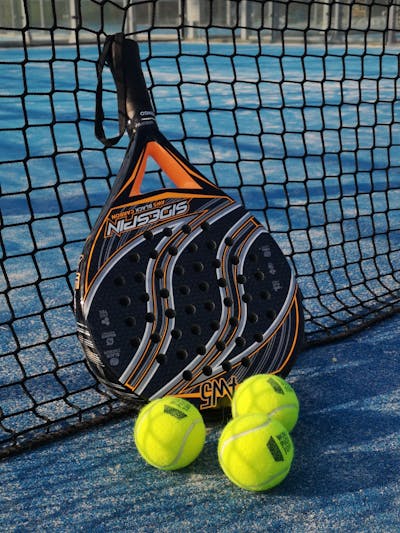 Padelracket met ballen op een zonnige padelbaan